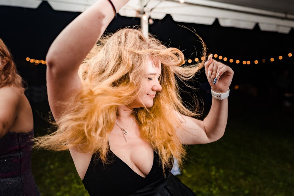 Woman with flowing blonde hair dances joyfully at nighttime outdoor event.
