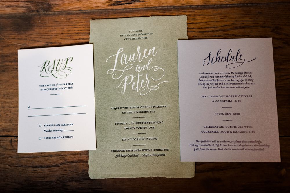 Wedding invitation suite featuring elegant calligraphy on sage green and white paper cards.