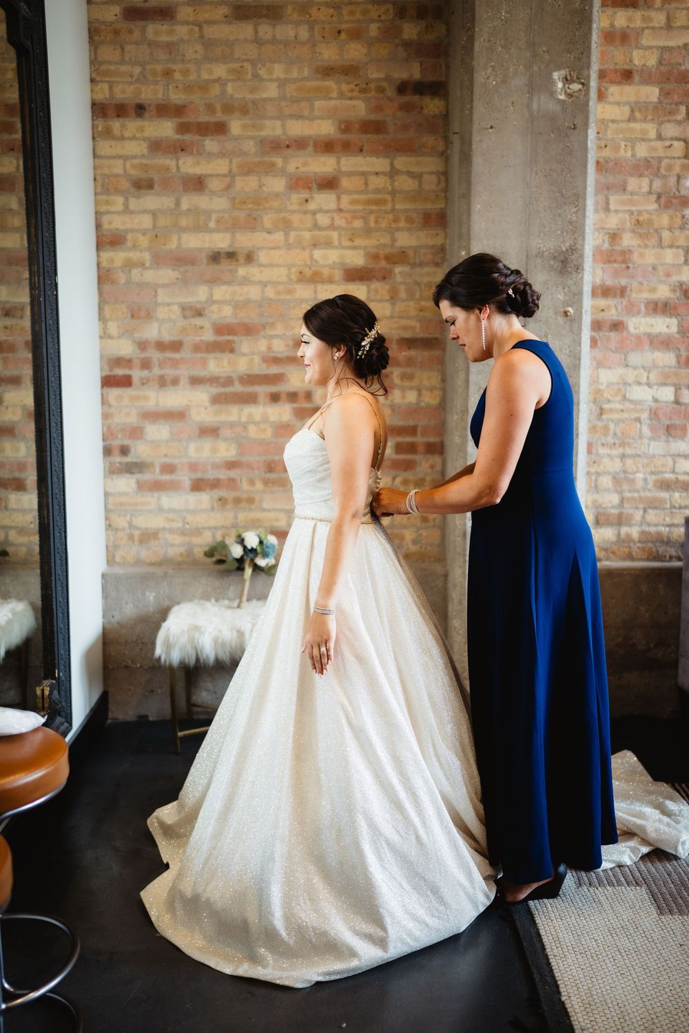 Final fitting of an elegant white wedding gown with navy blue bridesmaid dress.