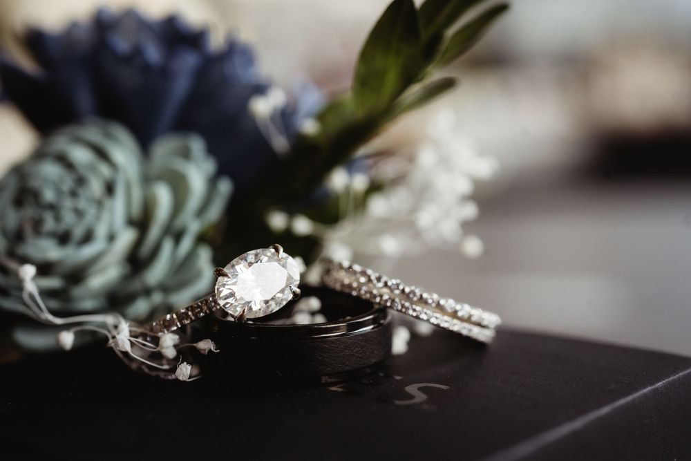Diamond engagement ring and wedding band set against dark background with succulents.