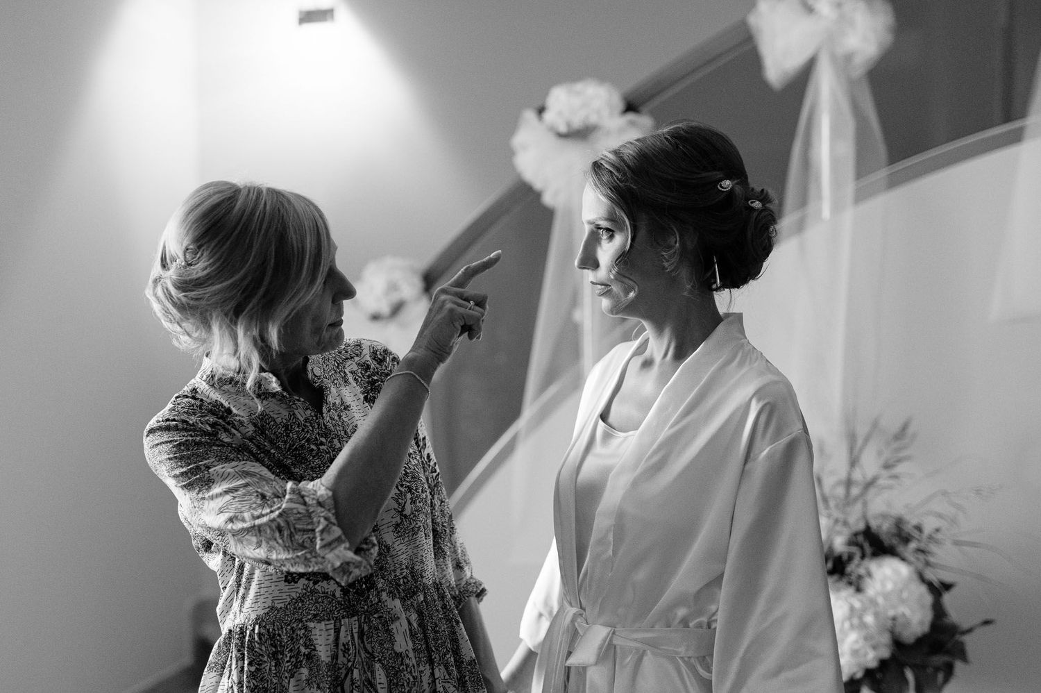A getting ready moment during wedding preparations show final touches being applied in a black and white photo.