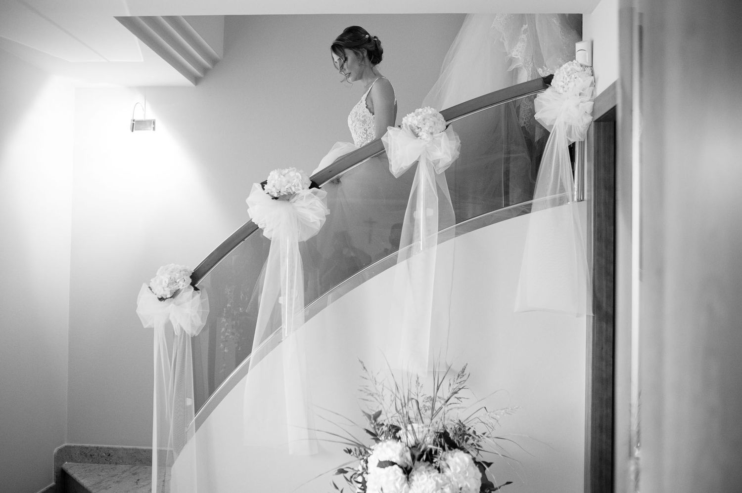 Wedding venue staircase decorated with white bows and floral arrangements in black and white.