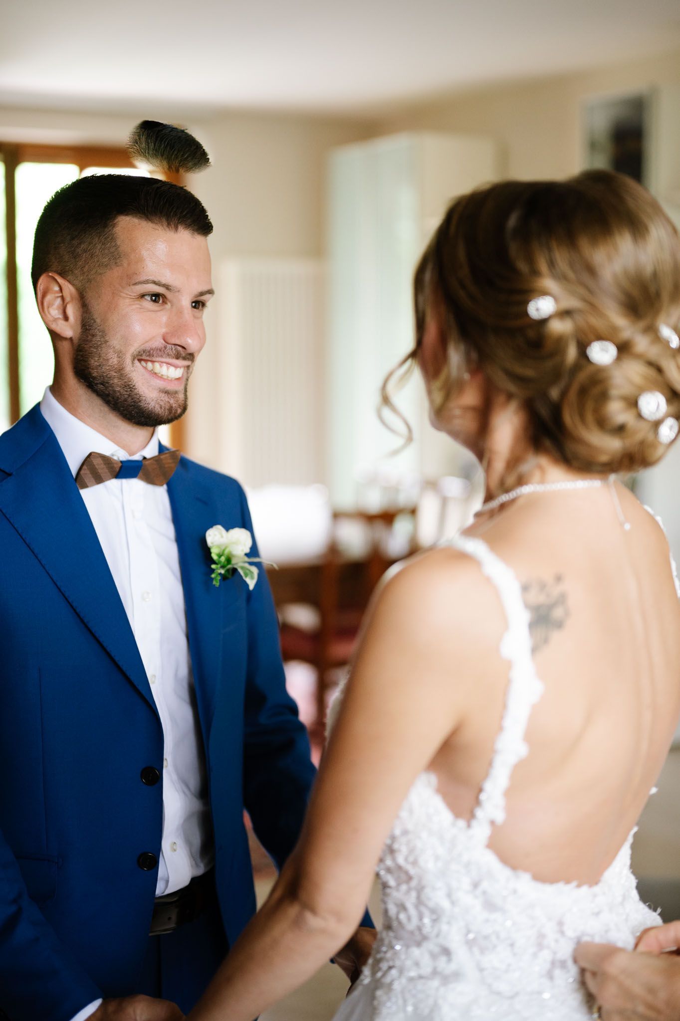 A groom in a navy suit with bowtie shares a special moment at a wedding.
