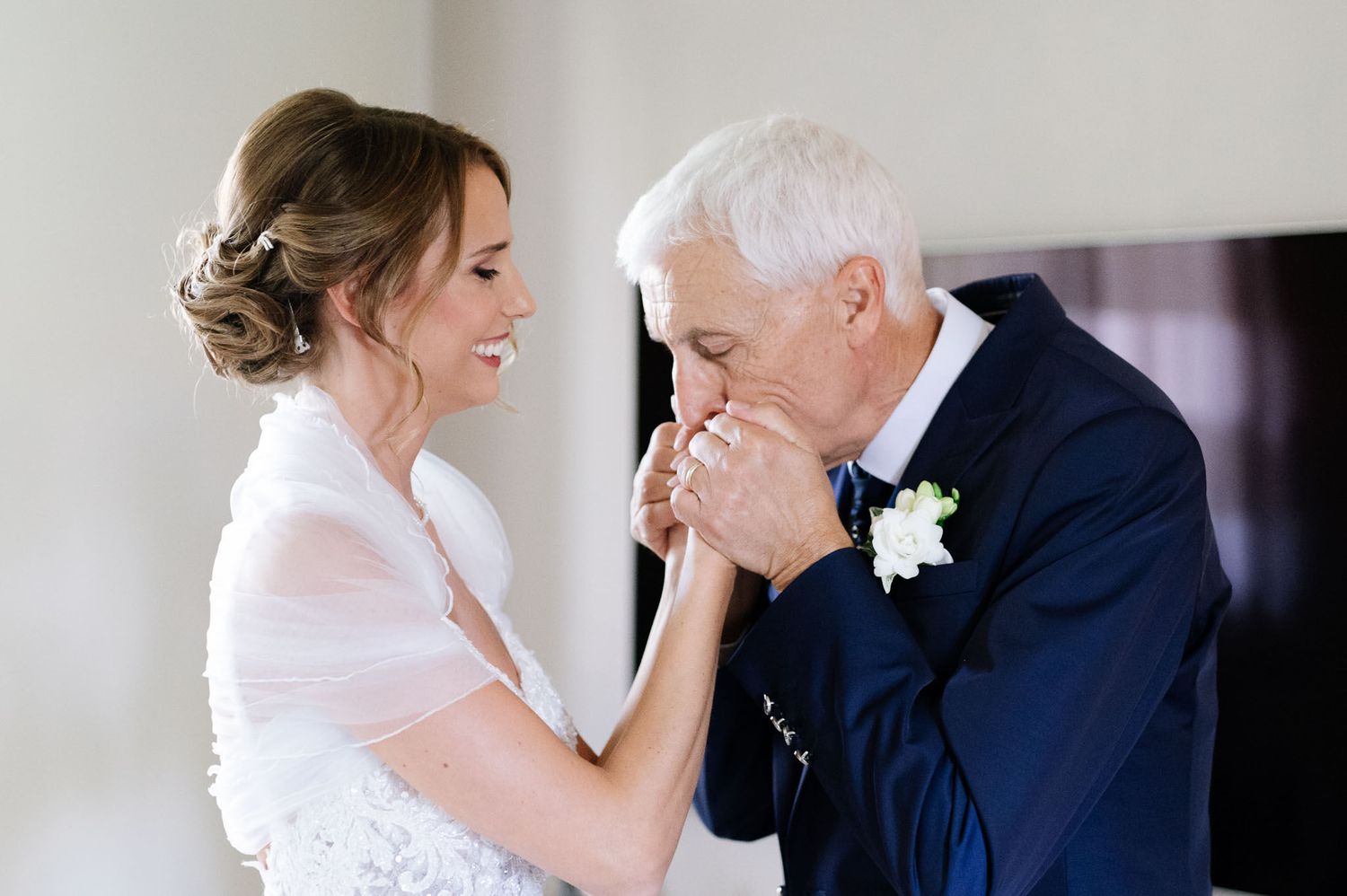 An emotional moment shared between a bride and older gentleman at a wedding.