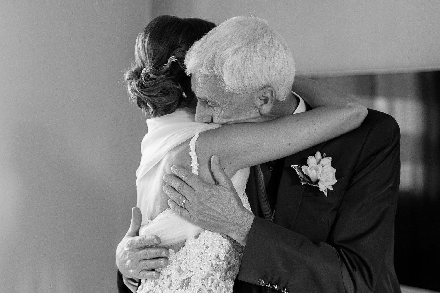A tender embrace captured in black and white between a bride and older gentleman.
