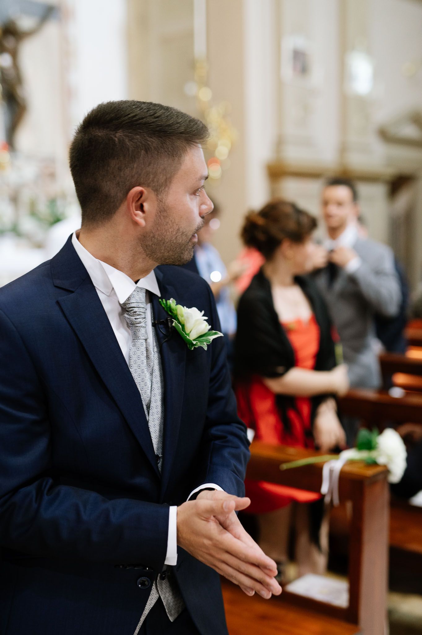 Formal church ceremony with attendees in formal attire and flower boutonniere.