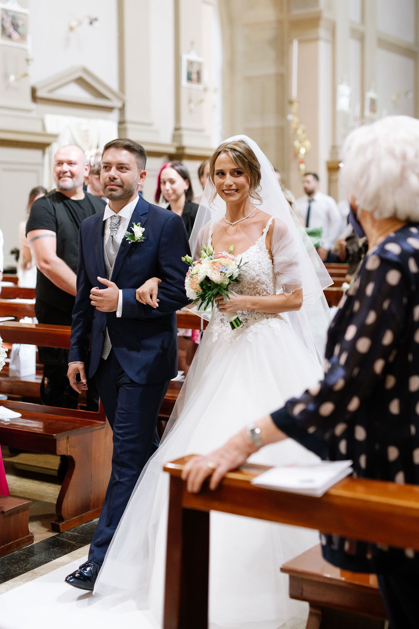 Wedding ceremony in a traditional church with guests seated in wooden pews.