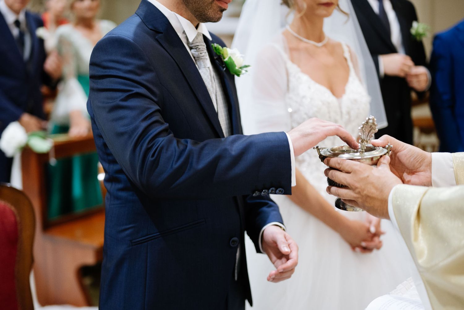 Traditional Catholic wedding ceremony showing exchange of rings at decorated church altar.
