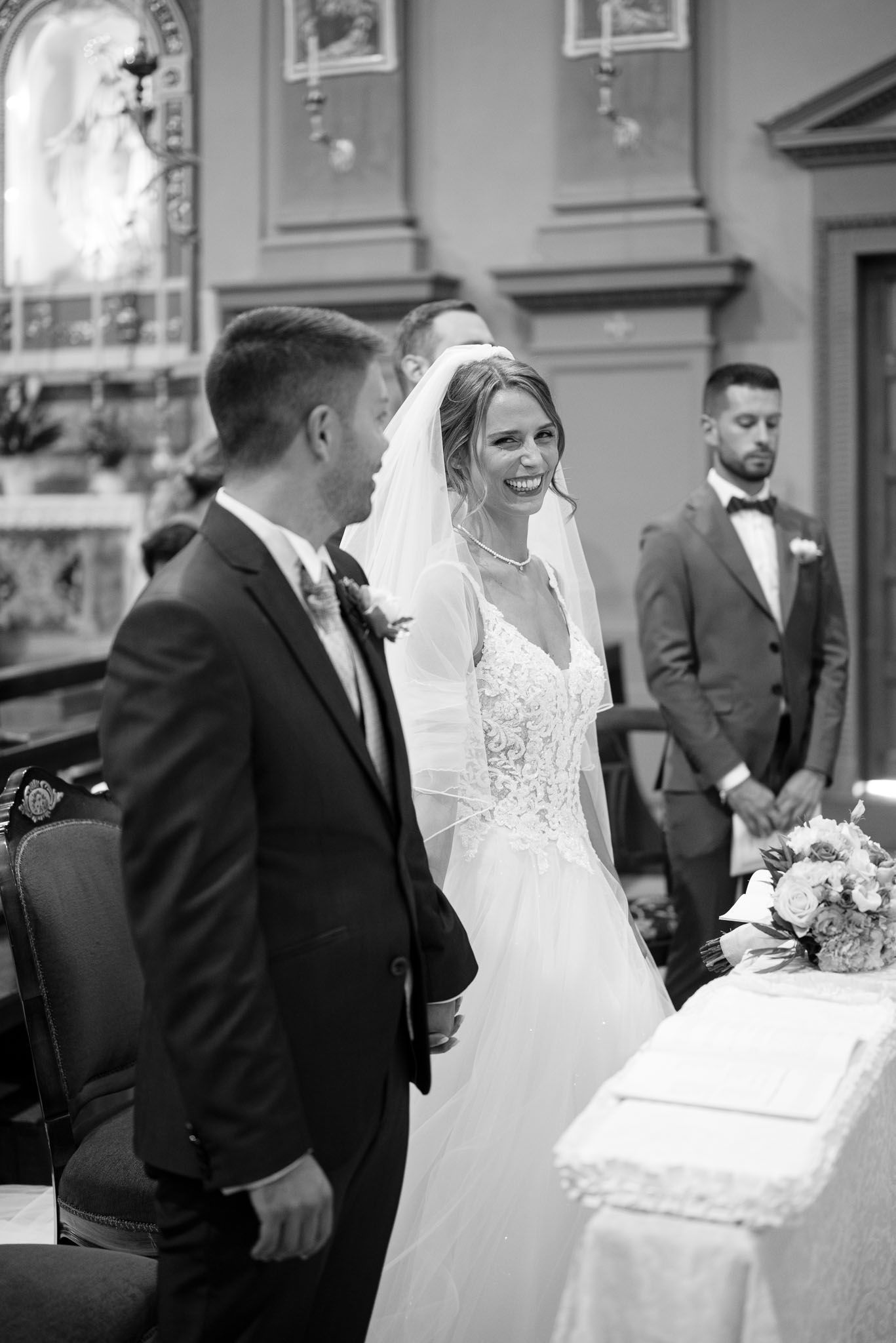 Candid moment during church wedding ceremony with couple at ornate altar with classic architecture.