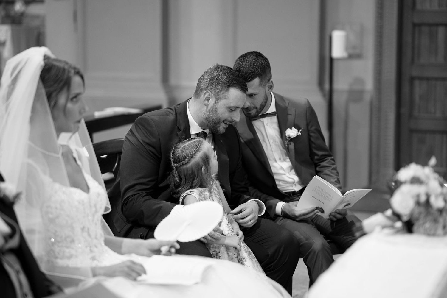 Intimate black and white moment during church wedding ceremony showing couple seated together.