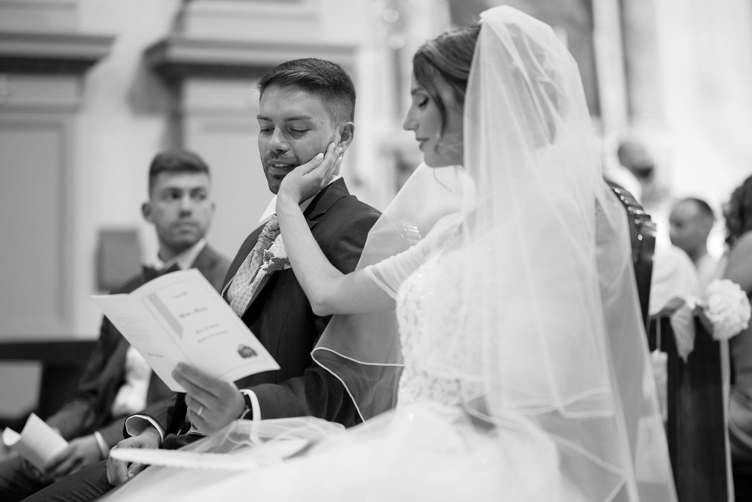 Black and white capture of intimate moment during traditional church wedding ceremony.