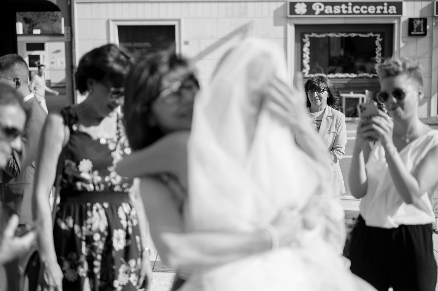 Blurred vintage-style photo of wedding guests outside Italian pasticceria.