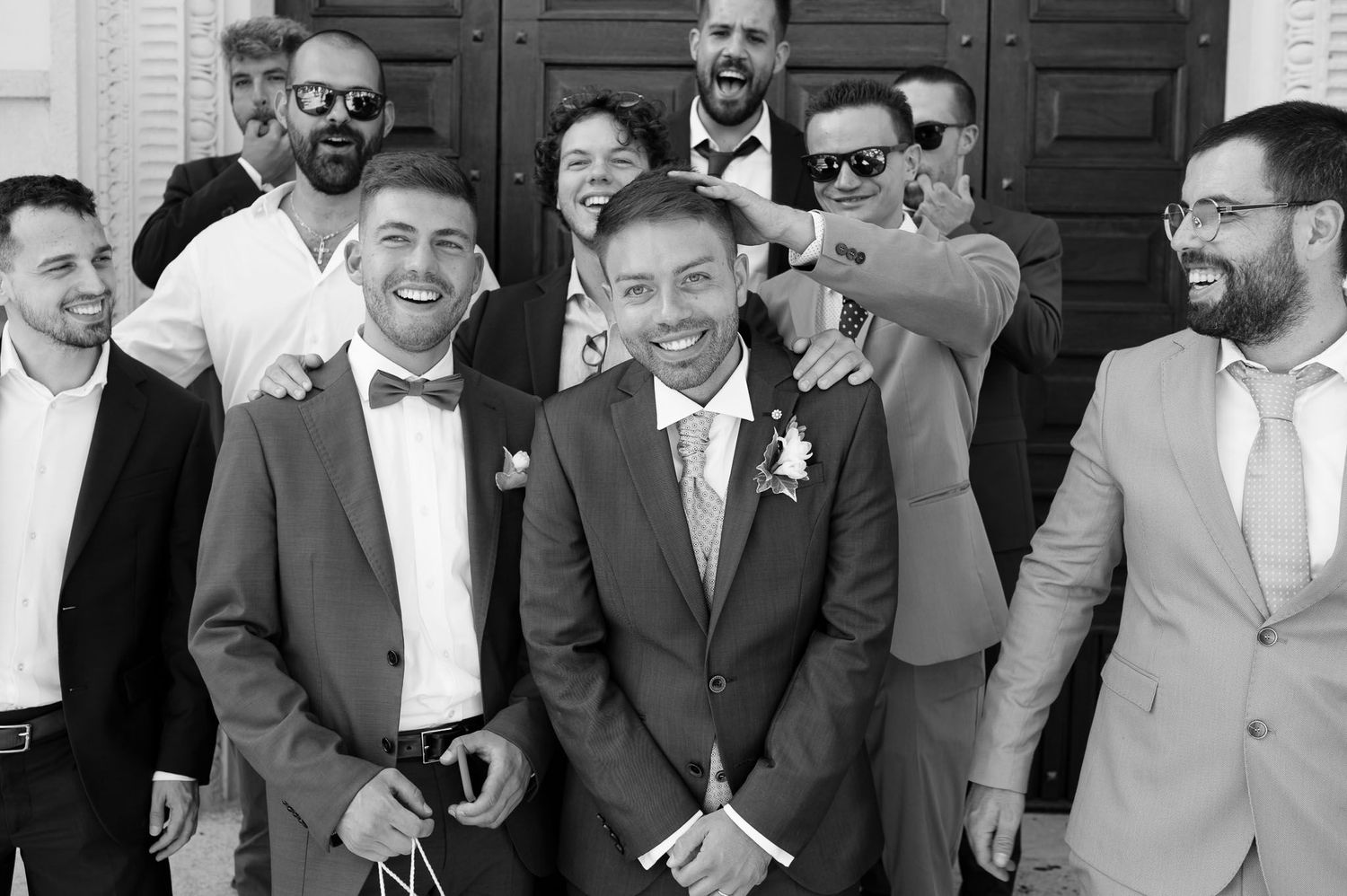 Groomsmen gather for casual group photo at wedding celebration.