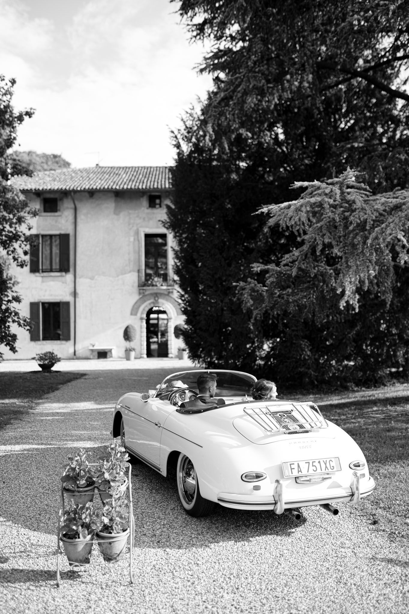 Vintage Porsche 356 Speedster parked outside a Mediterranean villa on a gravel driveway.