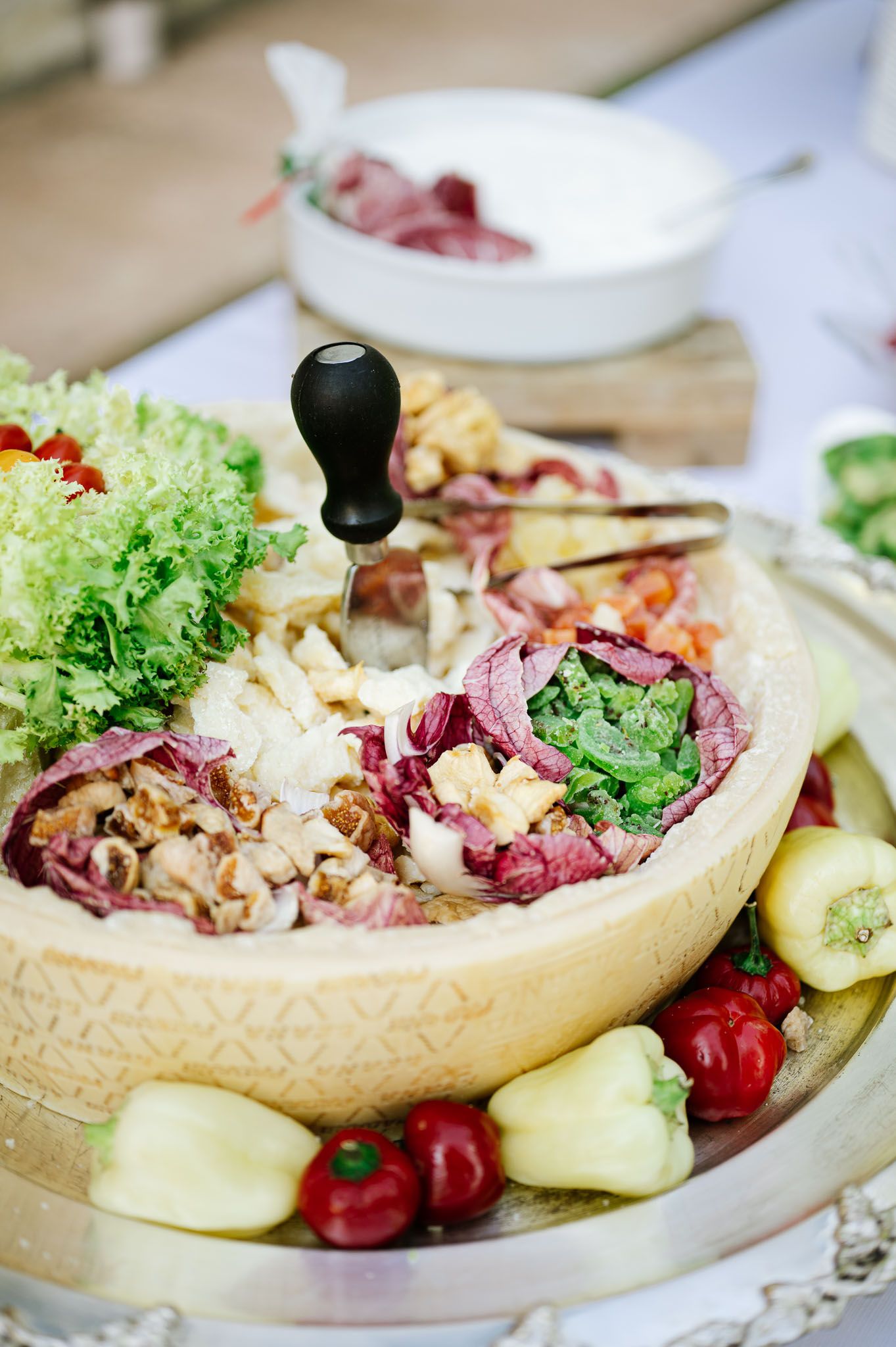 Fresh salad served in a decorative bowl with mixed greens, cherries and cucumber slices on an elegant platter.