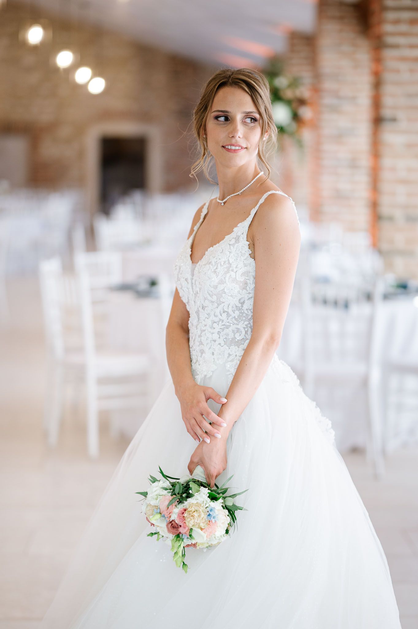 Elegant wedding dress with lace bodice and full tulle skirt in a rustic venue setting.