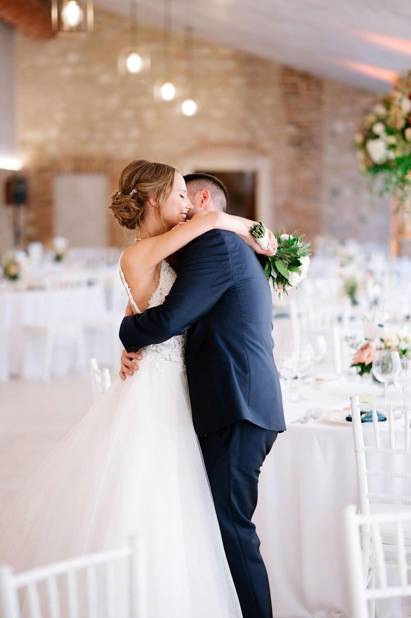 Romantic first dance moment in an elegant brick-walled reception venue.