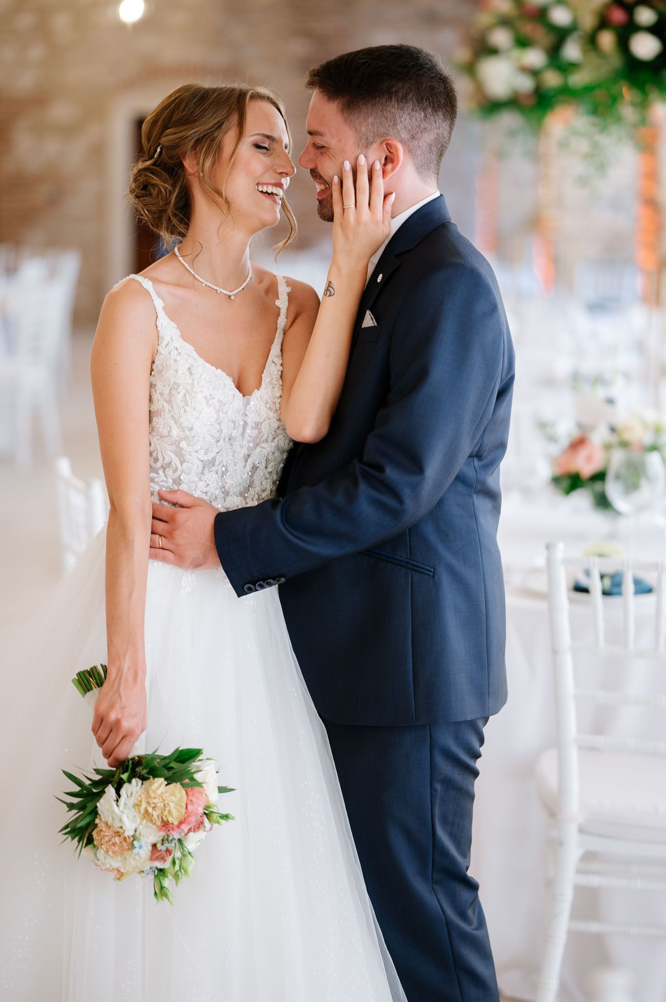 Tender moment between newlyweds in an elegant venue with exposed brick walls.
