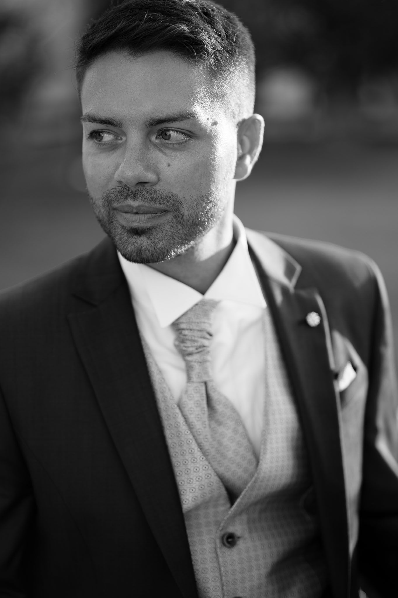 Black and white portrait of a groom in formal suit and tie.