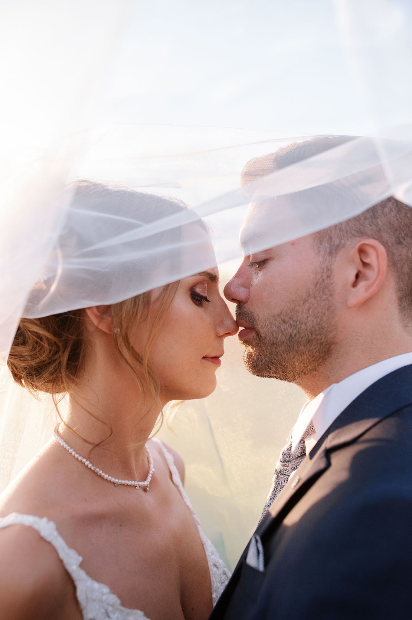 An intimate portrait of newlyweds sharing a tender moment under a flowing veil.