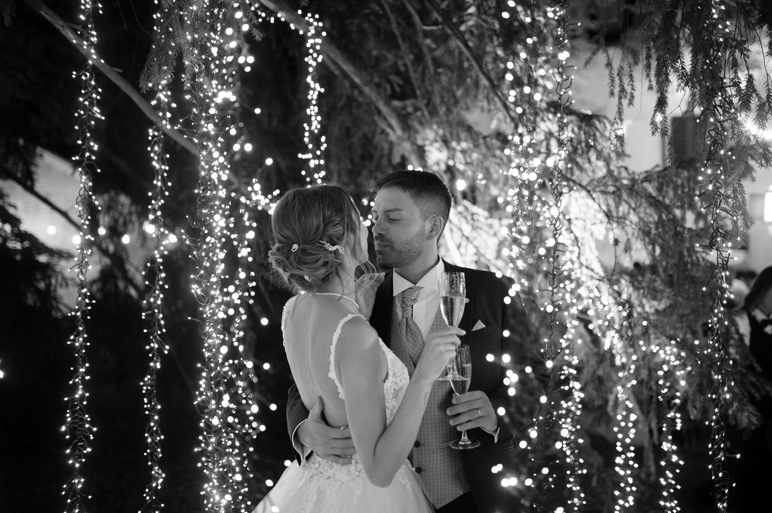 Black and white portrait under cascading lights creating romantic wedding ambiance.