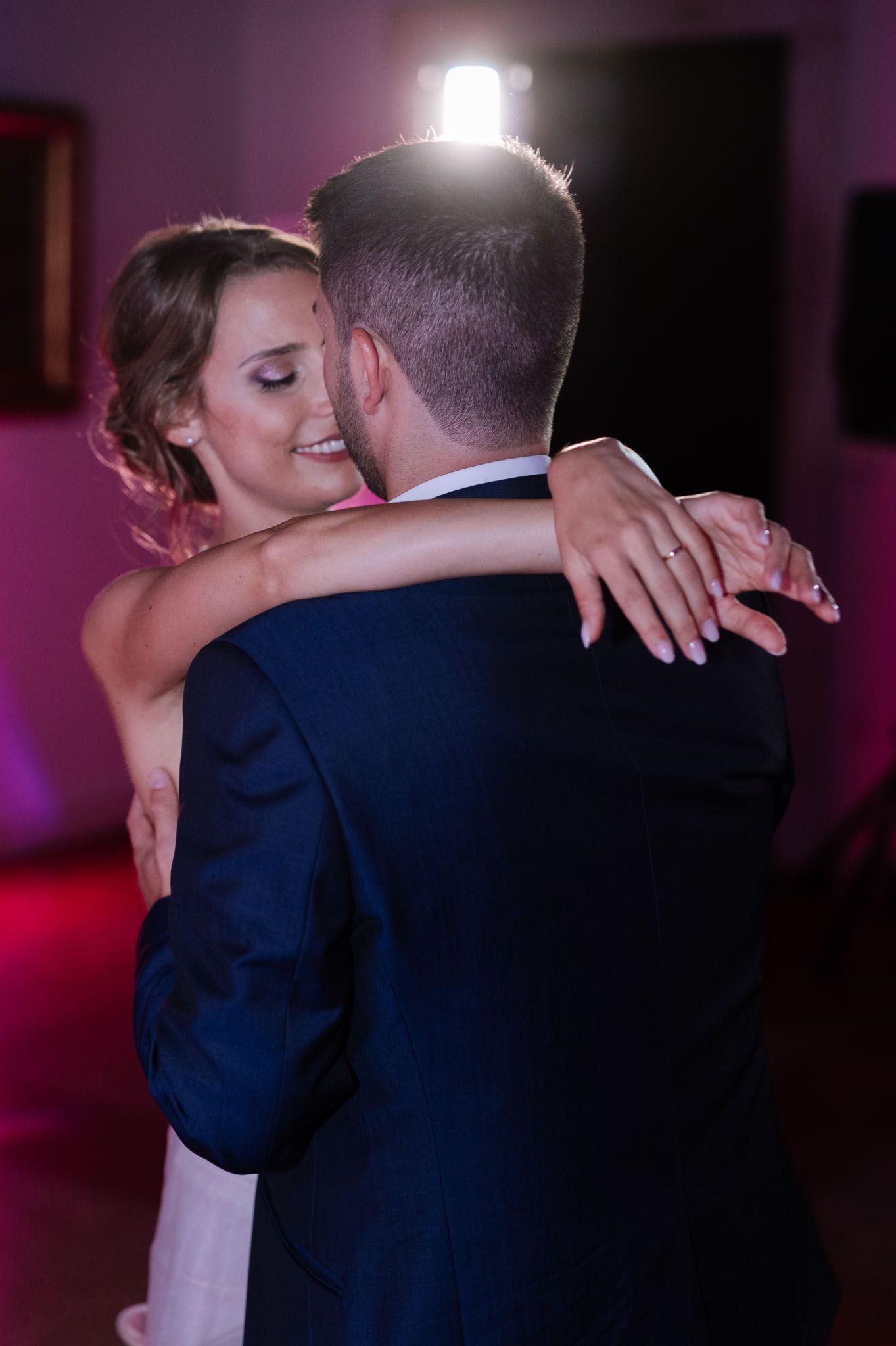 Intimate dance moment captured in purple-tinted lighting during wedding reception.