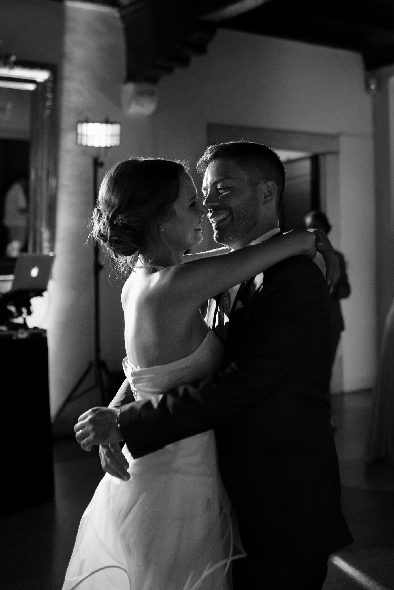 Black and white photograph capturing an intimate dance moment at an indoor wedding reception.