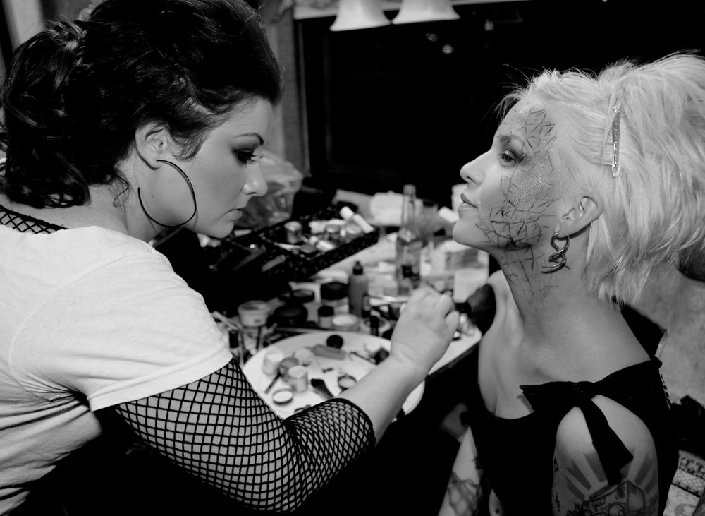 Black and white photograph of makeup application being done backstage.