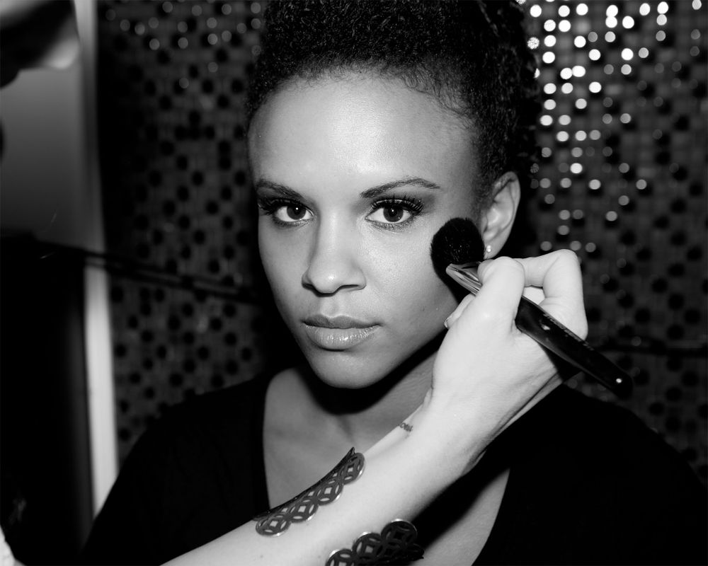 Black and white portrait showing makeup application with brush.