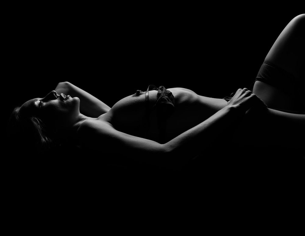 Dramatic low key photography with artistic body positioning and shadows.