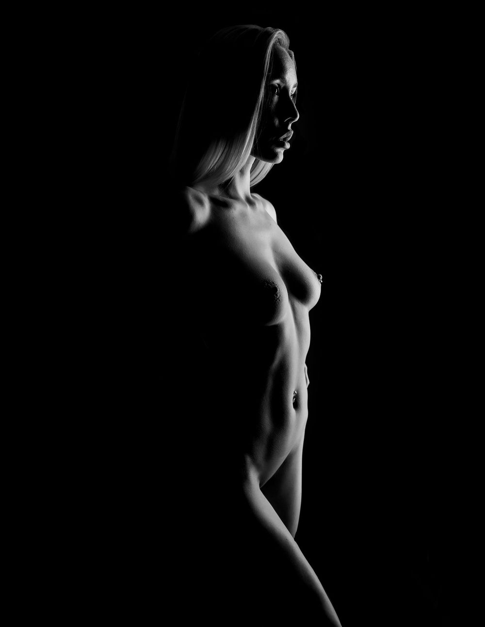 Fine art nude silhouette with dramatic side lighting and shadows.