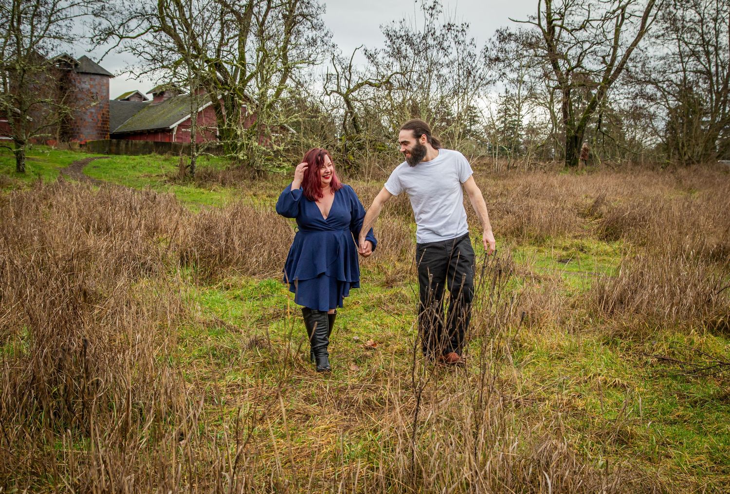 Couple walking together through a rustic field on an overcast day.