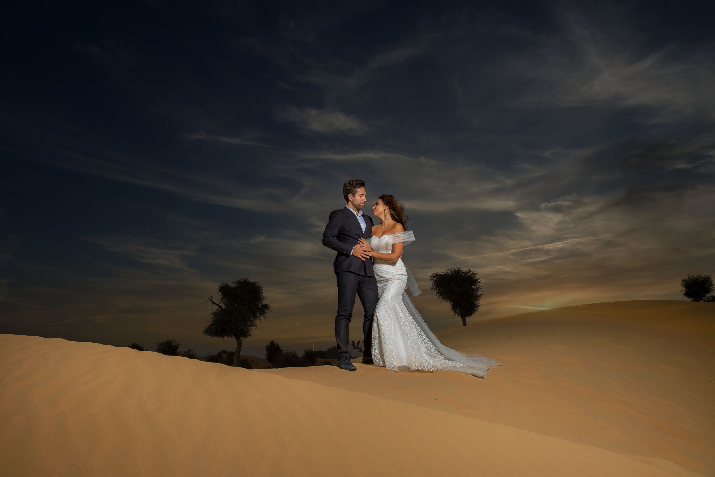 Couple standing near the desert in wedding attire.