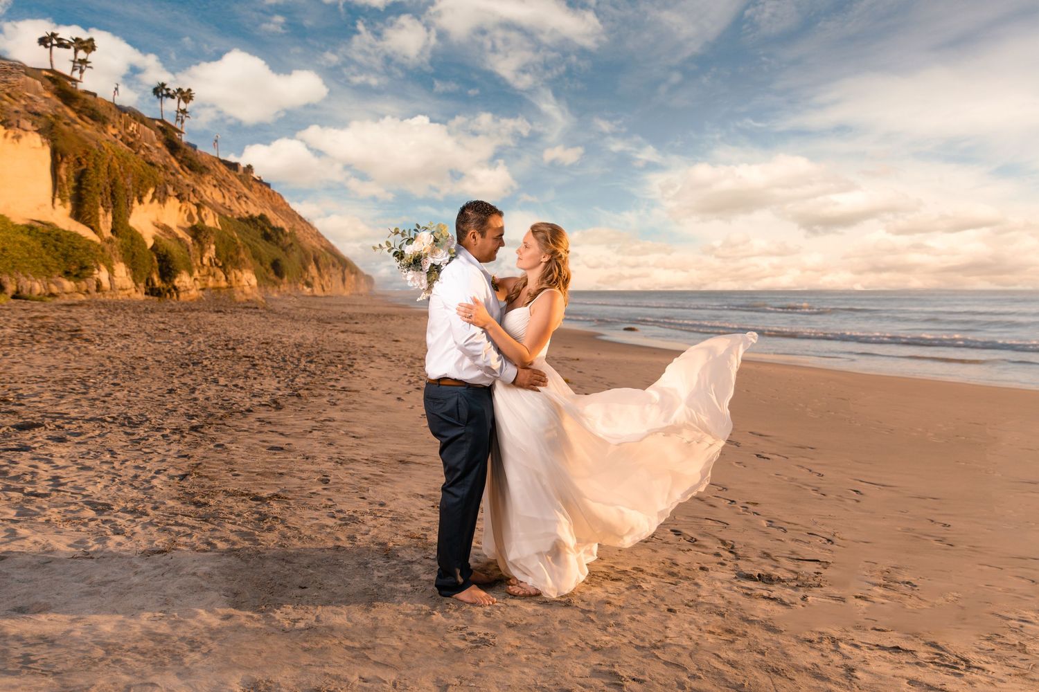 A romantic sunset beach scene shows a couple dancing on the sand with cliffs and ocean waves in the background.