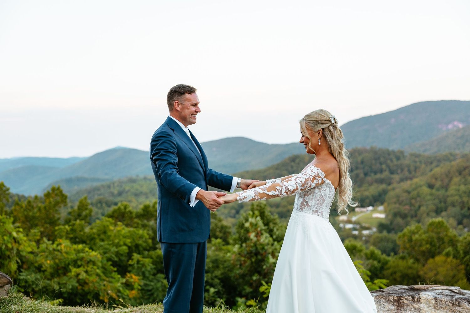 A romantic moment between a couple on a sunlit grassy field with trees in the background.