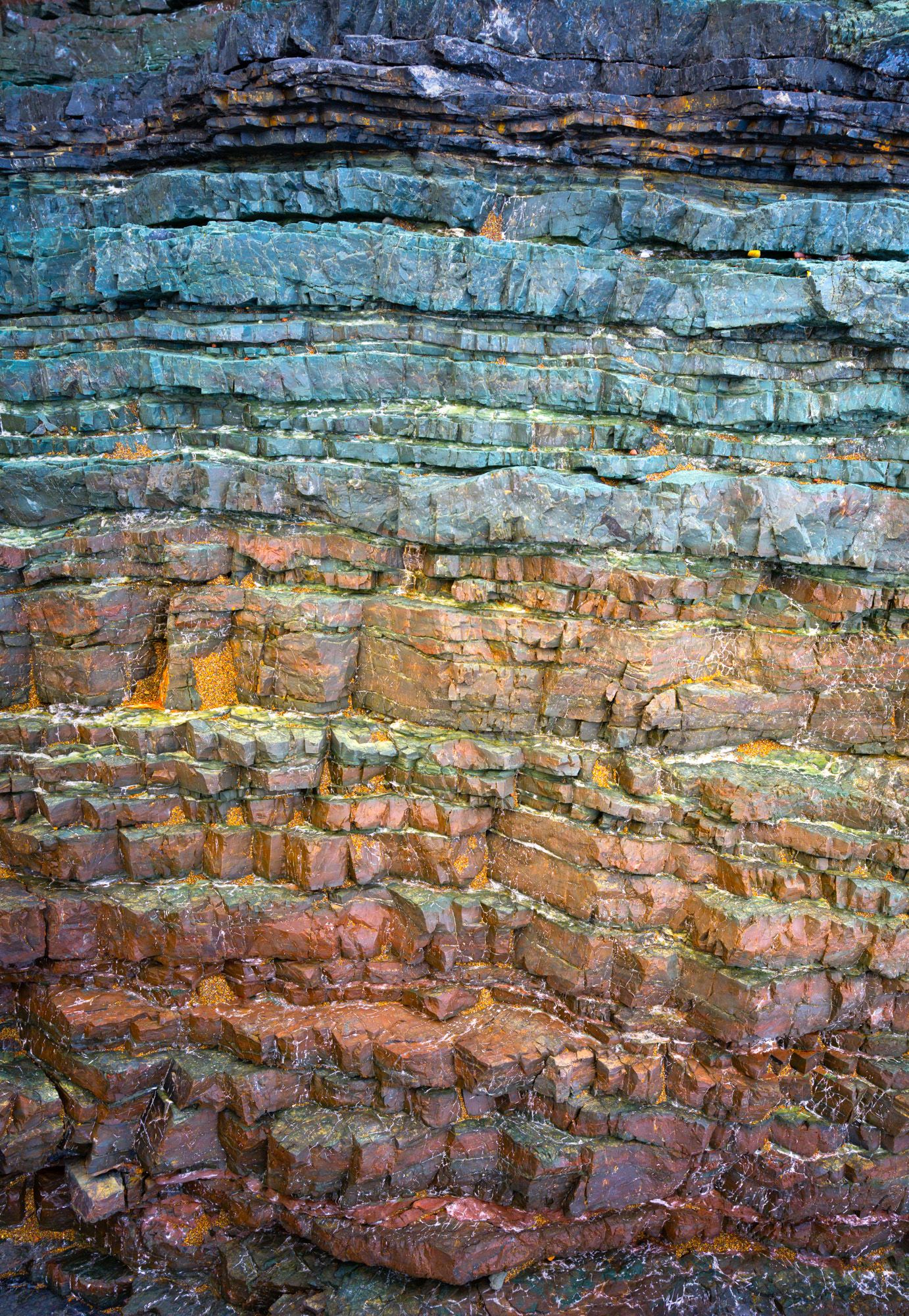 Colorful layered rock formations showing geological strata in shades of blue, orange and pink.