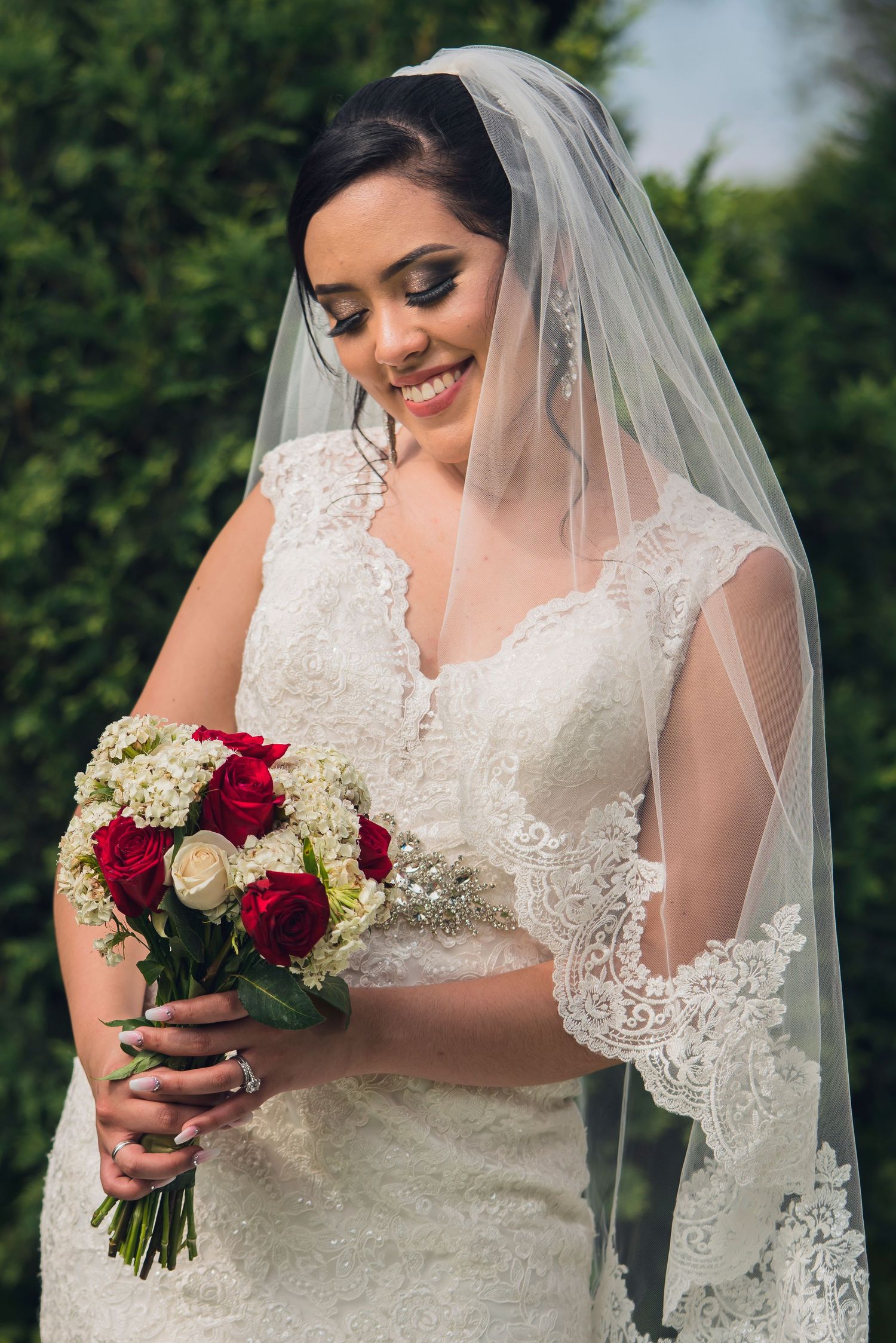 Elegant bridal portraits featuring lace wedding dress and bouquet with red and white roses.