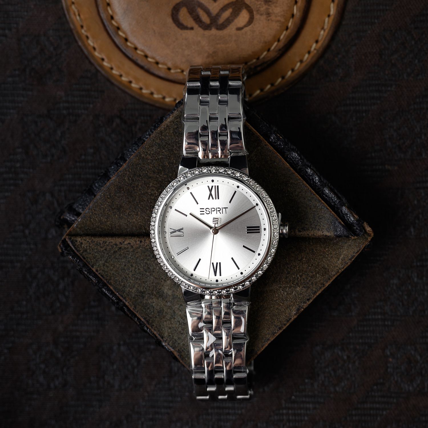 Détail artistique d'une montre de la marque Esprit, éclairée en studio sur fond texturé, ambiance de luxe