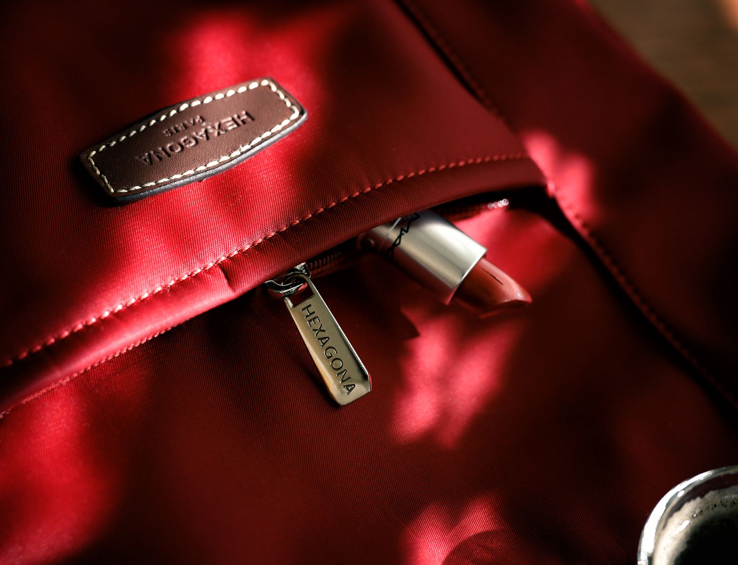 Gros-plan sur un sac à main rouge d'une marque de maroquinerie luxe, figurant un rouge à lèvres assorti