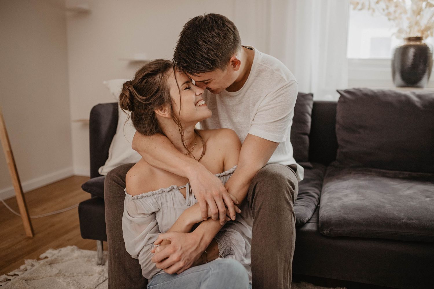 Tender indoor lifestyle portrait showing intimate moment on grey couch.