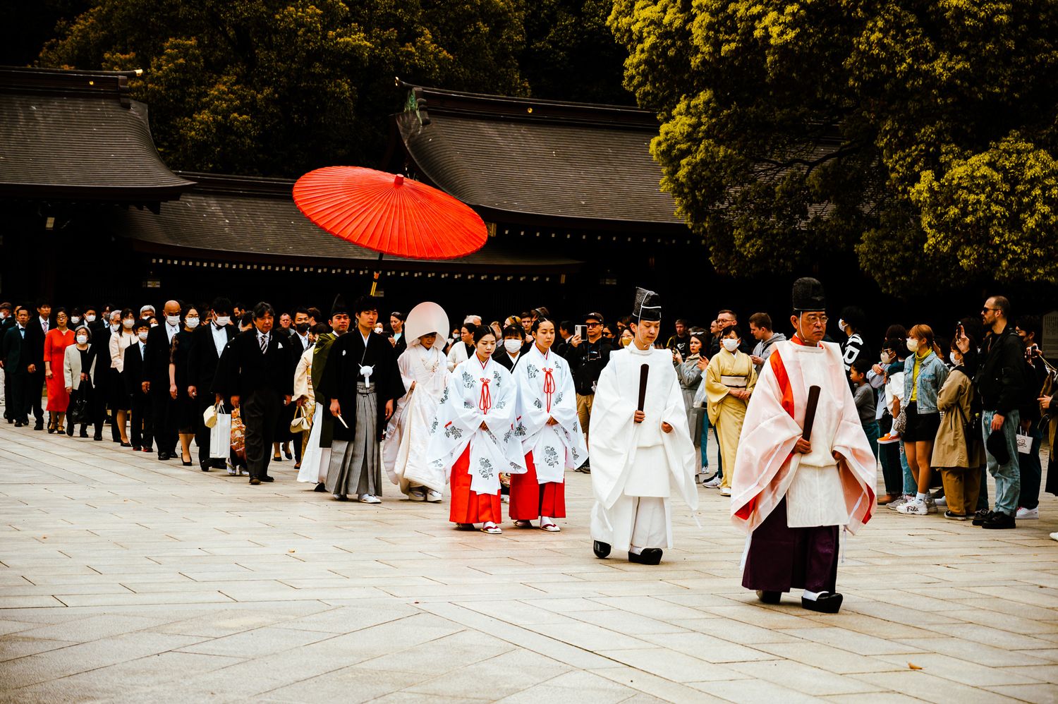 Traditional Japanese wedding procession at Meiji Shrine with red umbrella.