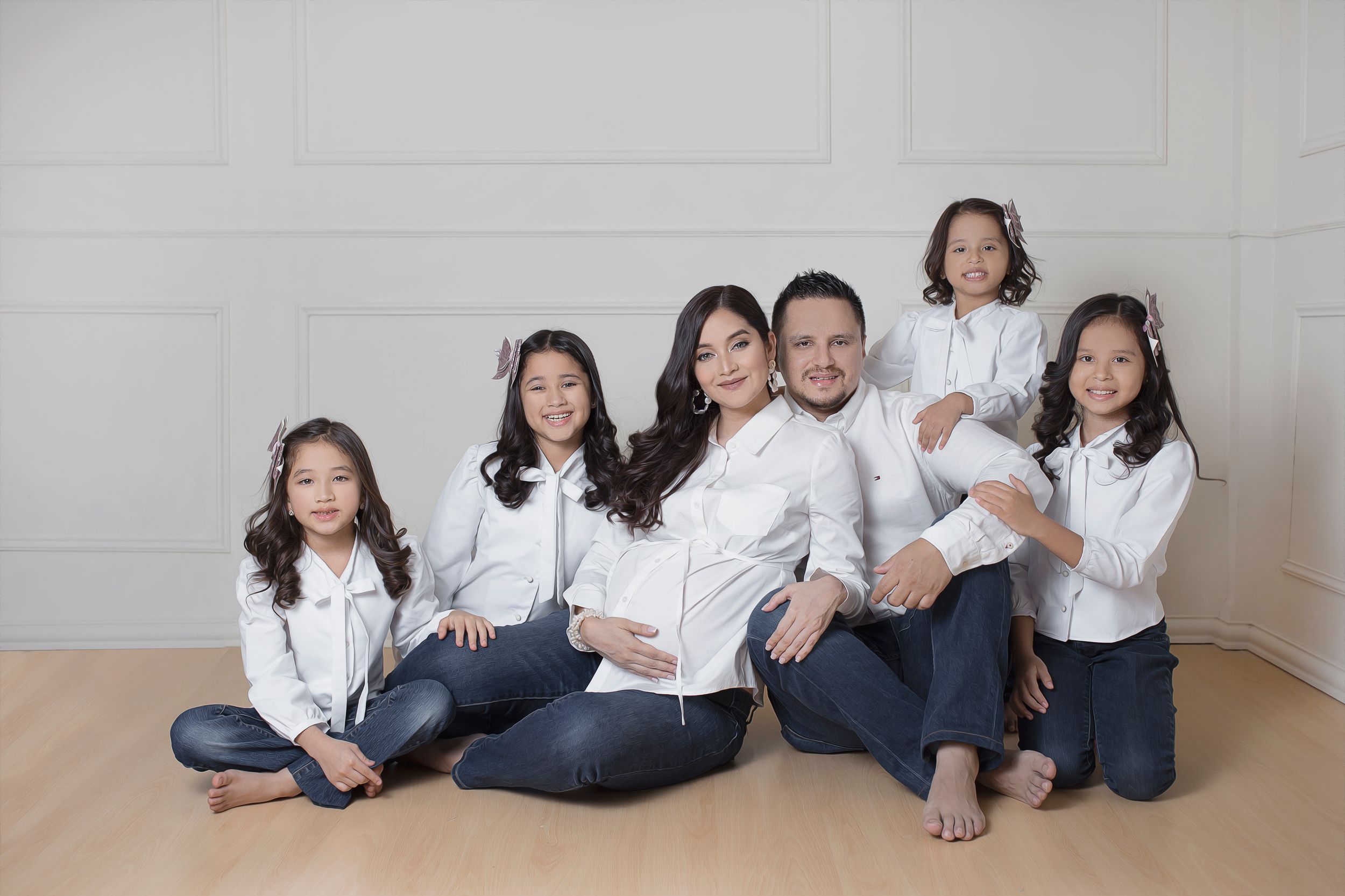 Family portrait session with everyone wearing coordinated white tops and blue jeans.