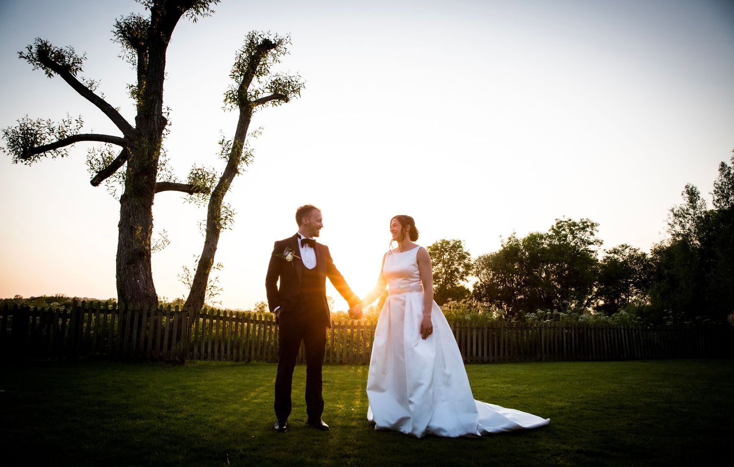 Sunset wedding photography session in garden setting with dramatic lighting.