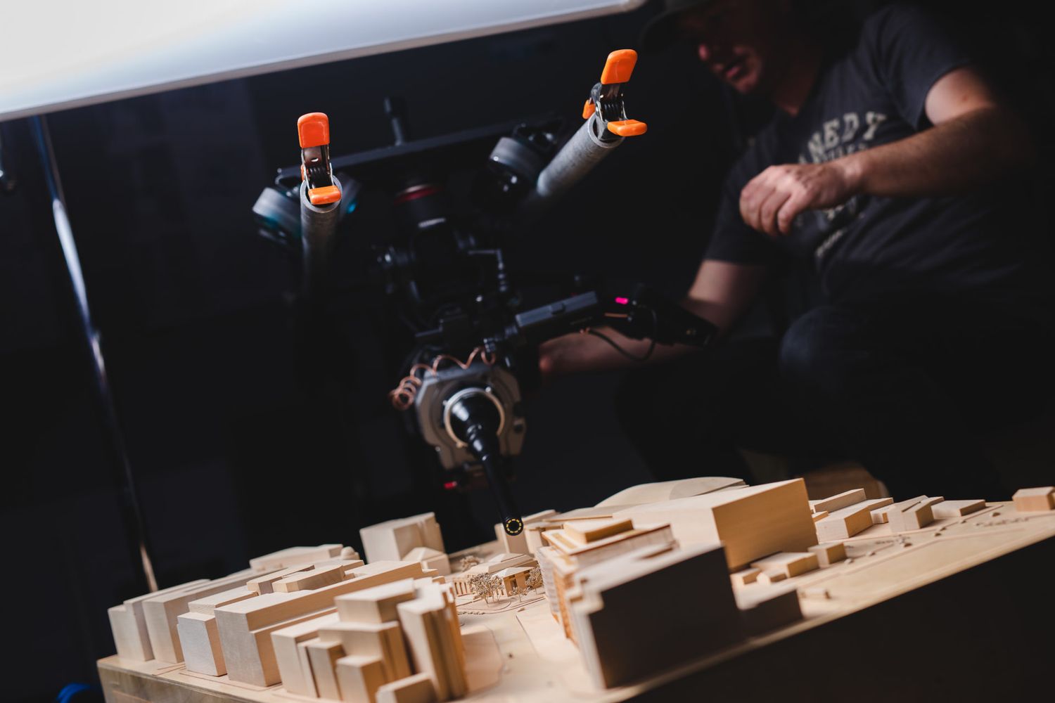 Close-up of camera equipment filming wooden architectural model structures.