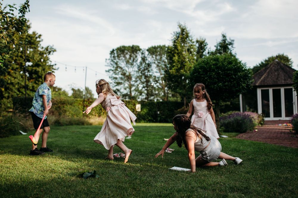 Wedding party dances and celebrates on a manicured lawn during outdoor reception.