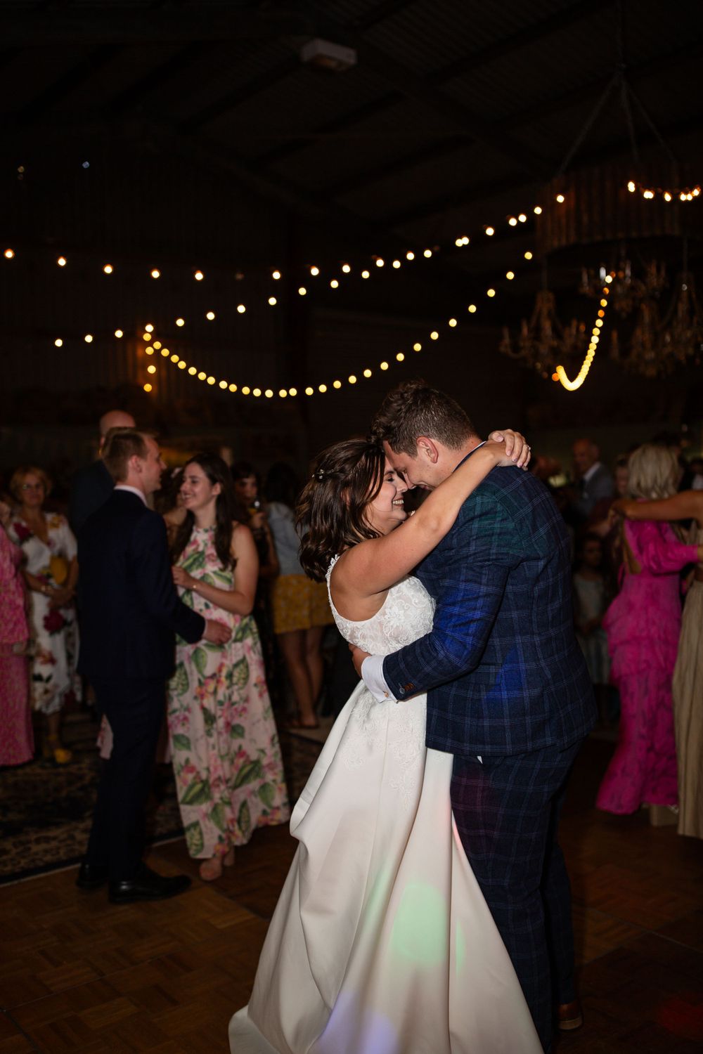 A couple shares their first dance under string lights at a romantic wedding reception.