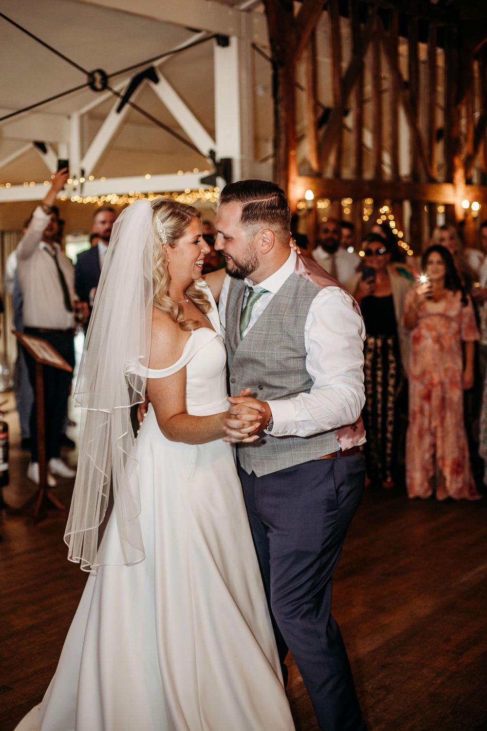 A couple shares an intimate moment during their first dance at a rustic wedding venue.