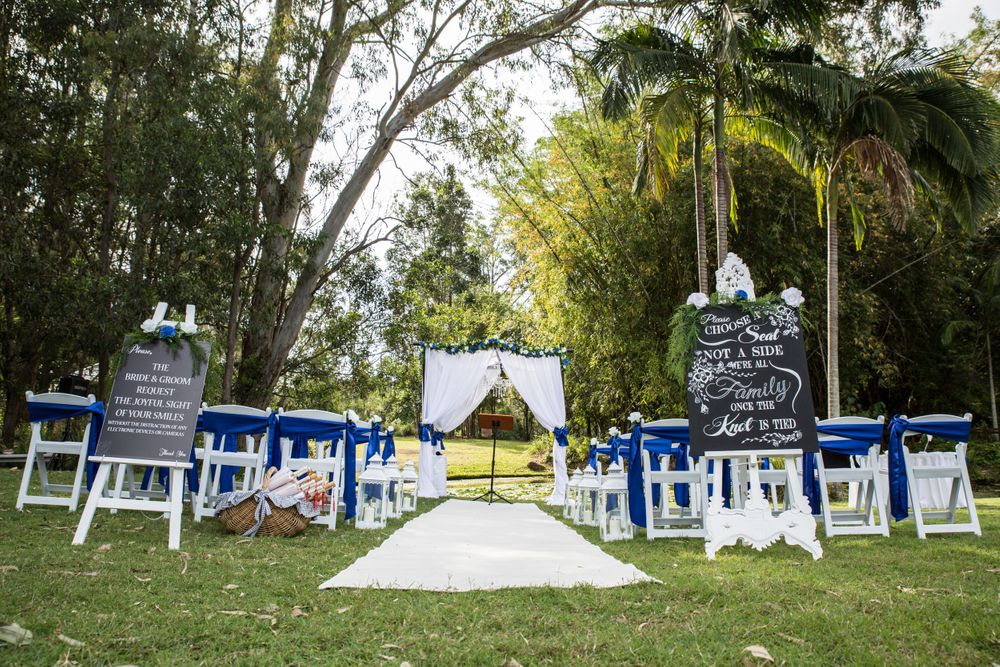 Panoramic view of an outdoor wedding venue with white chairs and blue decorative accents.