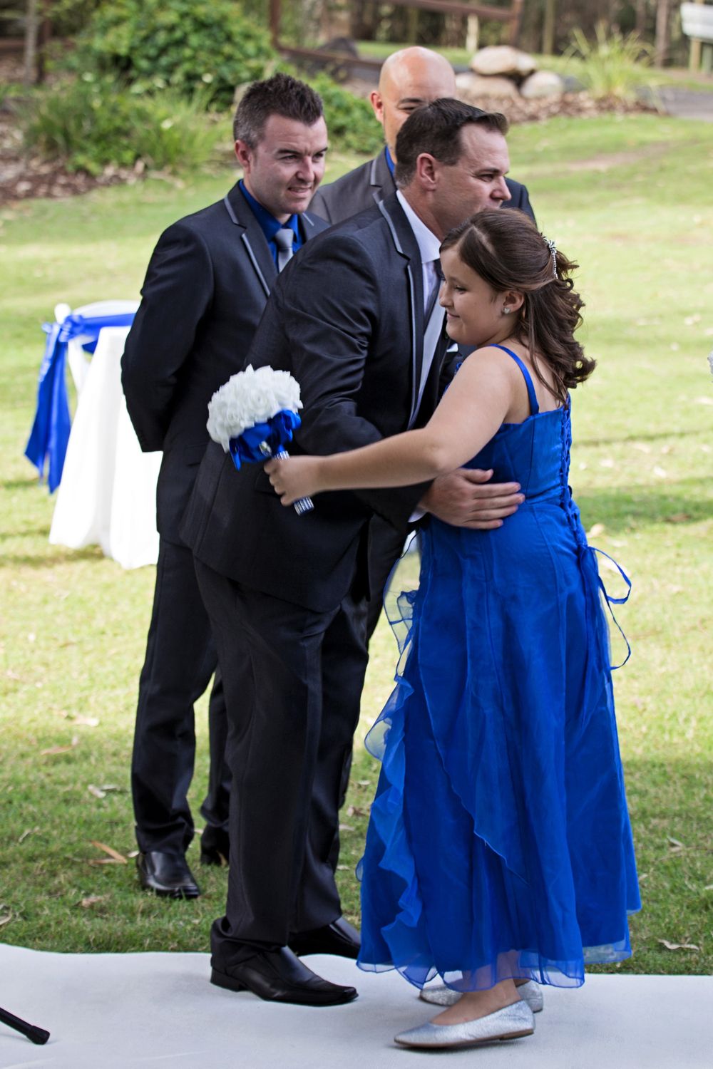 Wedding guests in formal attire embrace on an outdoor dance floor during celebration festivities.