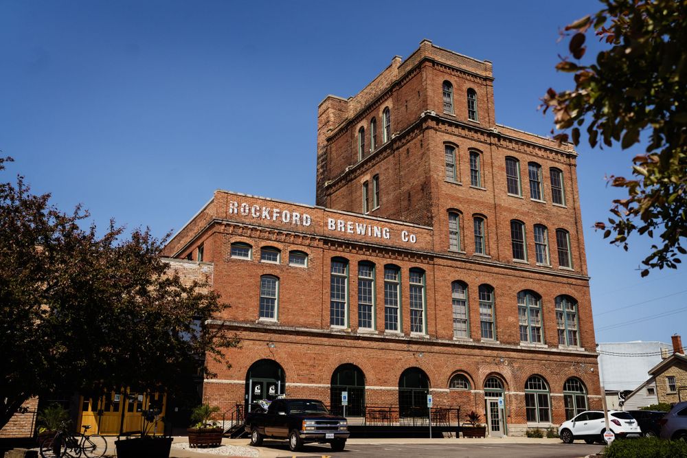 Historic red brick brewery building with ornate architecture against blue sky.